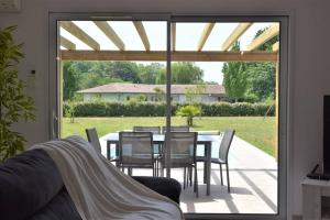 a patio with a table and chairs and a glass door at Calm house, swimming pool and garden in Bénesse-Maremne