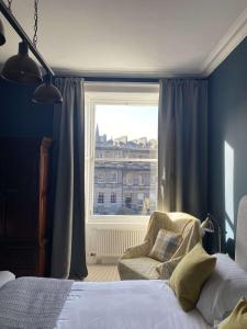 a bedroom with a bed and a chair and a window at West End Townhouse in Edinburgh