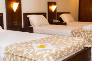 2 Betten in einem Hotelzimmer mit einer Speisekarte auf dem Bett in der Unterkunft Elo Hotels Express in Maringá