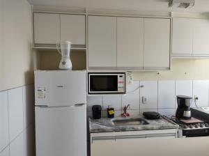 uma cozinha com armários brancos e um frigorífico branco em Apê - Parque Industrial - SJC - SP em São José dos Campos