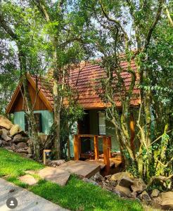 uma casa com um telhado vermelho na floresta em Cabana Mirim Estalagem Rural em Gramado