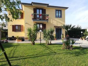 una casa gialla con palme nel cortile di B&B Villa Rosa vista Castello a SantʼAntonio Abate