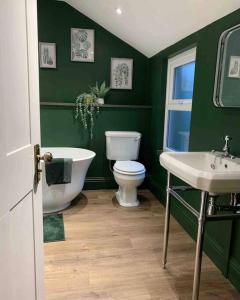 baño verde con bañera, aseo y lavamanos en No 11, Fishguard, Ideal for beach, coastal path and town! en Fishguard