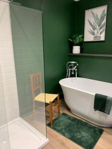 a green bathroom with a tub and a chair at No 11, Fishguard, Ideal for beach, coastal path and town! in Fishguard