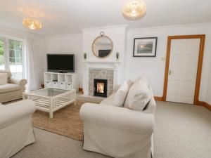 a living room with white furniture and a fireplace at Bwthyn Clai in Llangefni