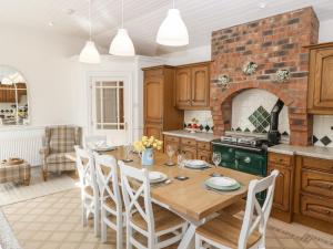 a kitchen with a wooden table and chairs in a room at Bwthyn Clai in Llangefni