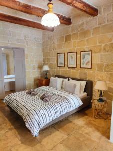 1 dormitorio con 1 cama grande en una pared de piedra en Gawhra B&B en Victoria