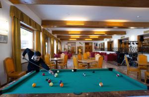 a man playing pool in a room with a pool table at Hotel San Giusto in Falcade