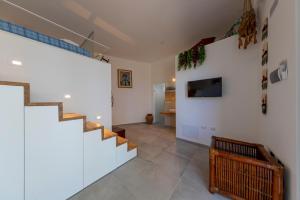sala de estar con escaleras y TV en la pared en Loft Bacco, en Cefalú