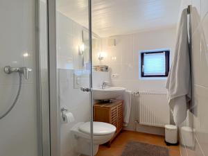 une salle de bain blanche avec toilettes et lavabo dans l'établissement Reetkate Reetdachhaus Friesen Chalet, à Tating