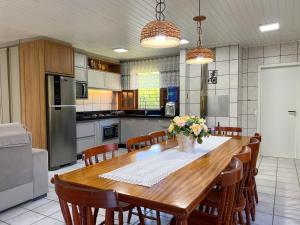 een keuken met een grote houten tafel en stoelen bij Casa de Campo no Caruru com açude e piscina in Tubarão