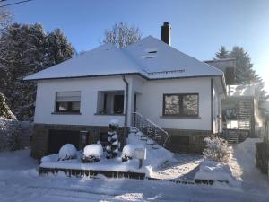 una casa bianca con la neve per terra di Holiday Apartment 4you a Butgenbach