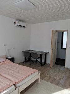 Schlafzimmer mit einem Bett, einem Schreibtisch und einem Tisch in der Unterkunft Lizi Apartman in Harkány