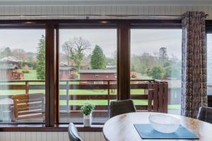 Un comedor con una mesa y un gran ventanal. en Birch Lodge 14 with Hot Tub, en Newton Stewart