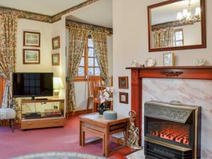 a living room with a fireplace and a tv at Toll Bridge Lodge in Banchory