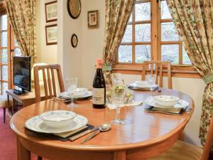 a wooden table with a bottle of wine and glasses at Toll Bridge Lodge in Banchory