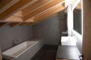 y baño con bañera blanca y lavamanos. en Chalet mit Kino und Jacuzzi in Gsteig b. Gstaad, en Gsteig
