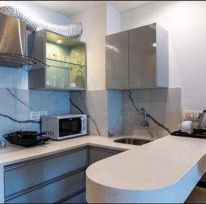 a kitchen with a white counter and a microwave at The Grand Anukampa Habitat Studio apartment in Jaipur