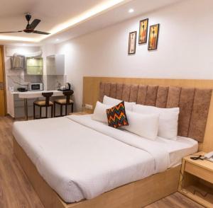 a bedroom with a large white bed and a kitchen at The Grand Anukampa Habitat Studio apartment in Jaipur