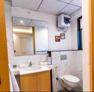 a bathroom with a sink and a toilet and a mirror at The Grand Anukampa Habitat Studio apartment in Jaipur