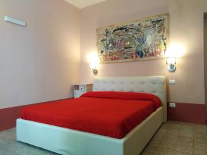 a bedroom with a red bed with a painting on the wall at Casa Saba in Orosei