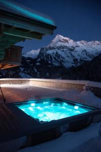 una bañera de hidromasaje en la nieve con una montaña en Chalet mit Kino und Jacuzzi in Gsteig b. Gstaad, en Gsteig