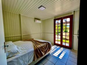 - une chambre avec un lit dans une pièce avec une porte dans l'établissement Casa de Campo no Caruru com açude e piscina, à Tubarão