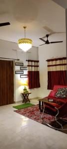 a living room with a red couch and a table at Raj Kuthir Homestays - Sobuj Potro in Bolpur