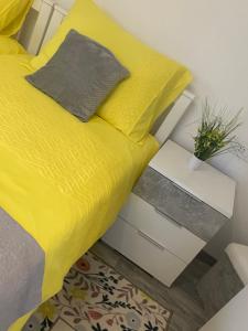 a bed with a yellow comforter and a side table at Bolkovac Apartman Ulica Donje selo 33 Fužine in Fužine
