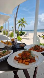 un tavolo con tre piatti di cibo su una spiaggia di Exclusivo apartamento frente al mar a San Pedro de Macorís