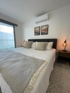 una camera da letto con un grande letto bianco e una finestra di Exclusivo apartamento frente al mar a San Pedro de Macorís