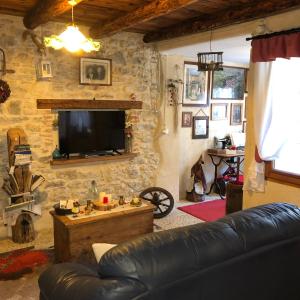 a living room with a leather couch and a television at CASA ANGELA Stayerat a SEGUSINO Valdobbiadene in Segusino