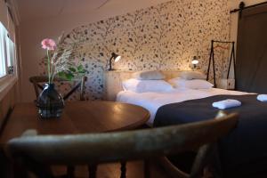 un dormitorio con 2 camas y una mesa con un jarrón de flores en Porcus Campus en Aarle-Rixtel