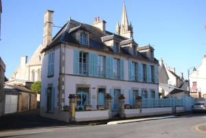 an old building with blue shutters on a street at Chambres Chez Mounie in Arromanches-les-Bains