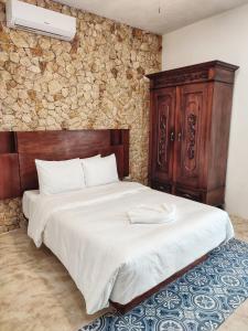 - une chambre avec un grand lit et une tête de lit en bois dans l'établissement Boutique Casa Azuli Santiago, à Mérida