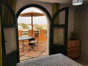 eine offene Tür zu einer Terrasse mit einem Tisch und einem Sonnenschirm in der Unterkunft Gîte Forest Kasbah in Kasba et Tahar