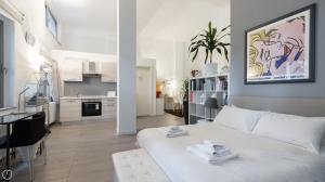 a white bedroom with a white bed and a kitchen at Casa Olimpia in Bresso