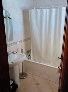 a bathroom with a sink and a shower curtain at Erike Guest House in Carvoeiro