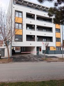 a white apartment building with a parking lot at Apartman KLM in Pančevo