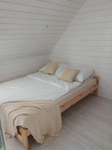un letto con lenzuola e cuscini bianchi in una stanza di Domki Biała Mewa Sarbinowo a Sarbinowo