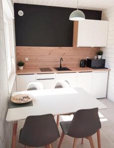 - une cuisine avec une table et des chaises blanches dans l'établissement Domki Biała Mewa Sarbinowo, à Sarbinowo