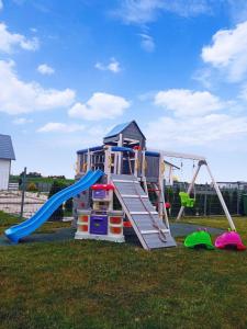 a playground with a slide in a yard at Domki Biała Mewa Sarbinowo in Sarbinowo