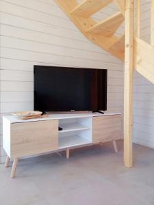 a flat screen tv sitting on top of a wooden entertainment center at Domki Biała Mewa Sarbinowo in Sarbinowo