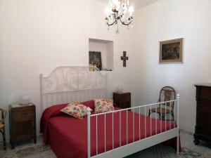 a bedroom with a bed with red sheets and a chandelier at Fichi e Gelsomino - Casa Vacanze in Donnalucata
