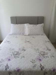 a bed with a white comforter with flowers on it at De lucca home Studio in Florianópolis