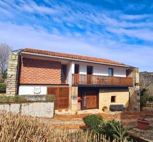 a brick house with a balcony and a fence at Posada Los Calderones in Santillana del Mar