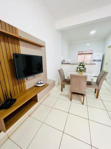 un soggiorno con TV e tavolo con sedie di Nossa Casa, Sua Casa 01 - Excelente Localização a Parati