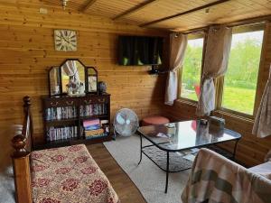 a living room with a table and a clock on the wall at Silver Springs Farm Lodge in Dingestow