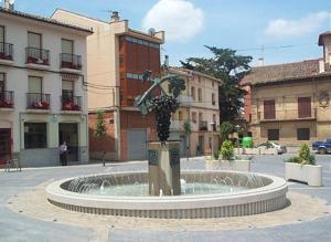 a fountain in the middle of a street with buildings at Pensión Úbeda in Fuenmayor