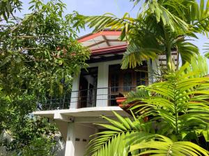 una casa con balcón en medio de árboles en Green Lodge en Weligama